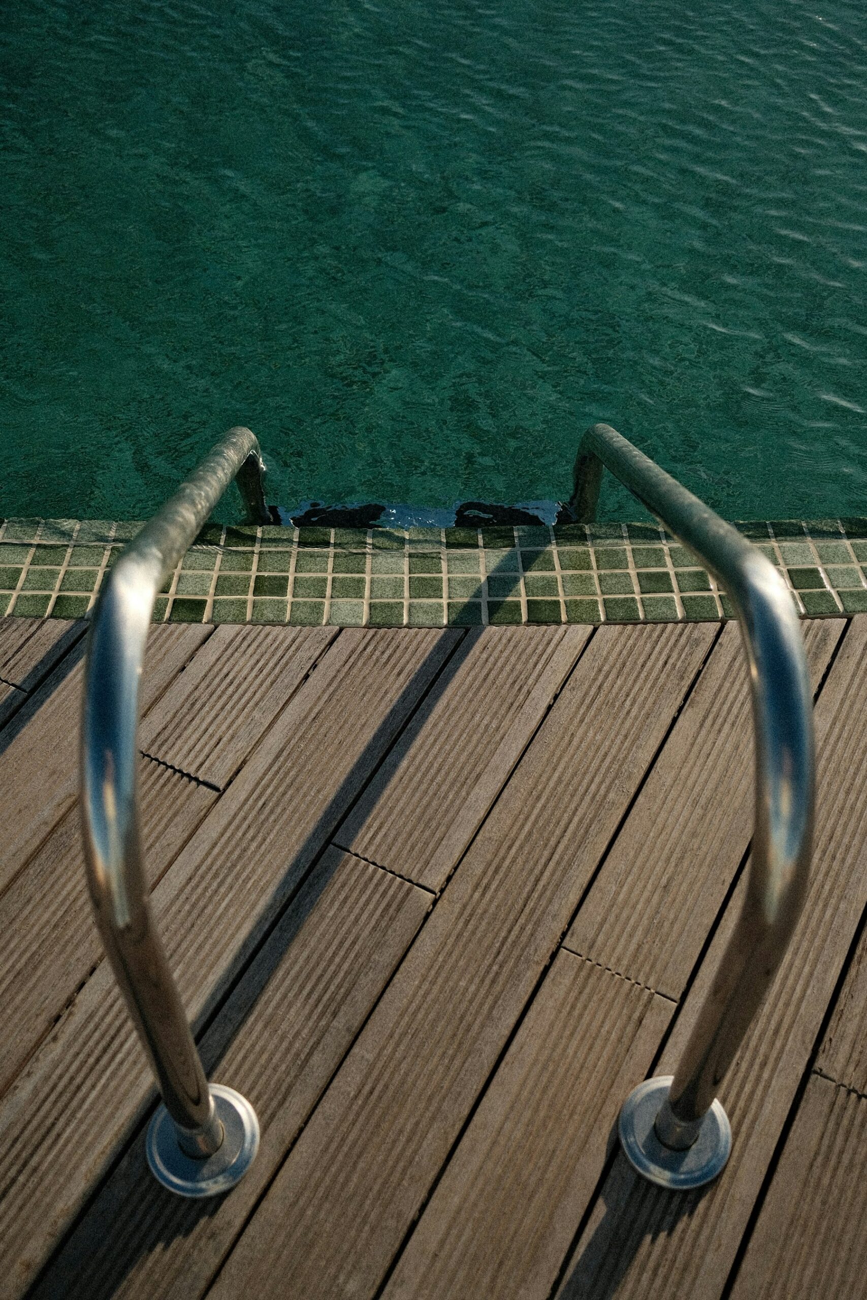 Échelle de piscine descendant dans une eau turquoise et transparente